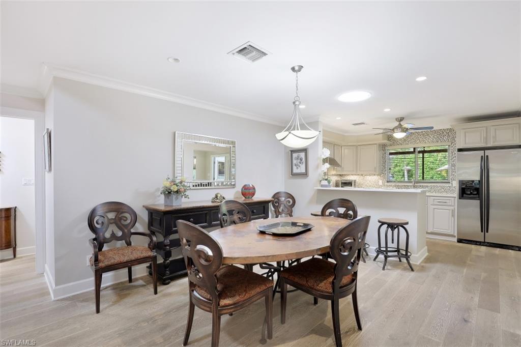 1199 9th Avenue North Naples, FL 34102 - Photo 8 of 24 a view of a dining room and livingroom with furniture wooden floor a rug a painting and a chandelier