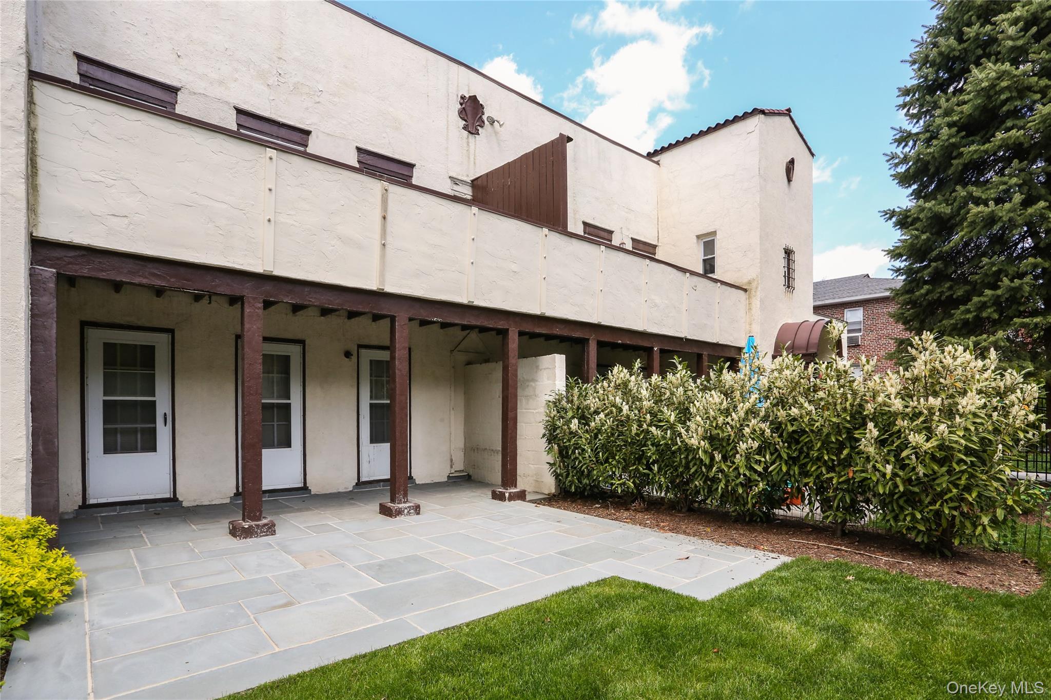 107 Kensington Road, Unit 5 Bronxville, NY 10708 - Photo 2 of 17 Back of house featuring stucco siding, a patio, and a yard