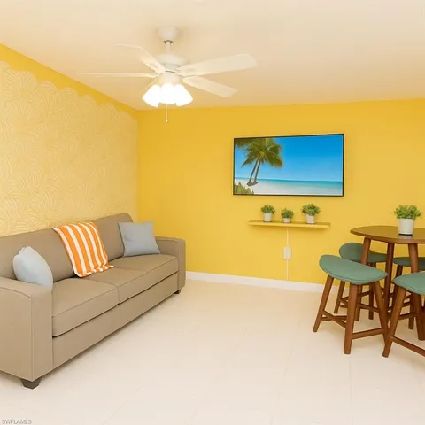 a living room with a couch and a dining table with a large window