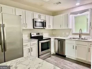 a kitchen with granite countertop a sink stainless steel appliances and white cabinets