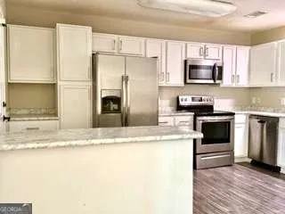 a kitchen with stainless steel appliances granite countertop a refrigerator a stove top oven a sink and dishwasher