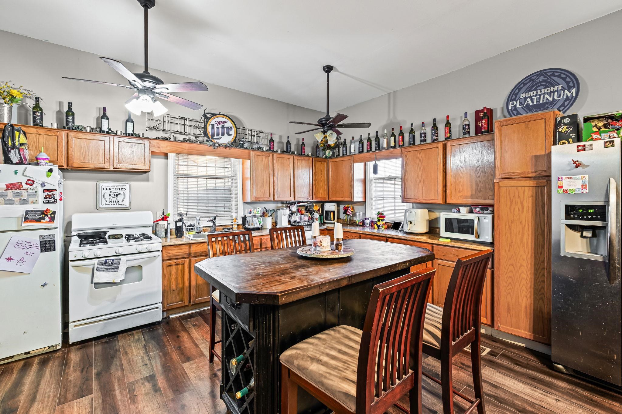 a kitchen with stainless steel appliances granite countertop a stove a refrigerator a oven a sink a dining table and chairs with wooden floor