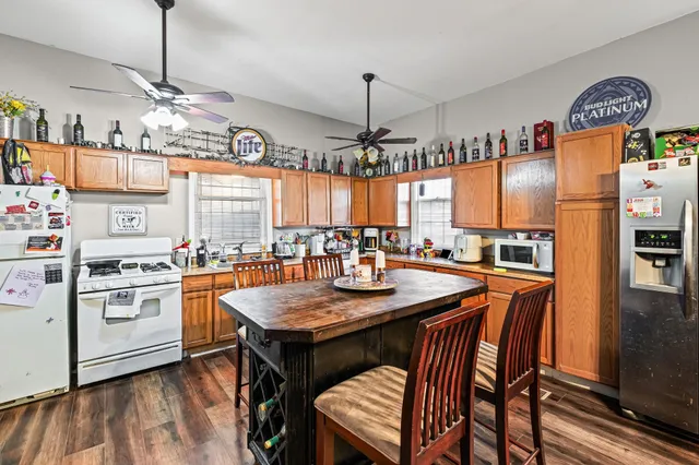 a kitchen with stainless steel appliances granite countertop a stove a refrigerator a oven a sink a dining table and chairs with wooden floor