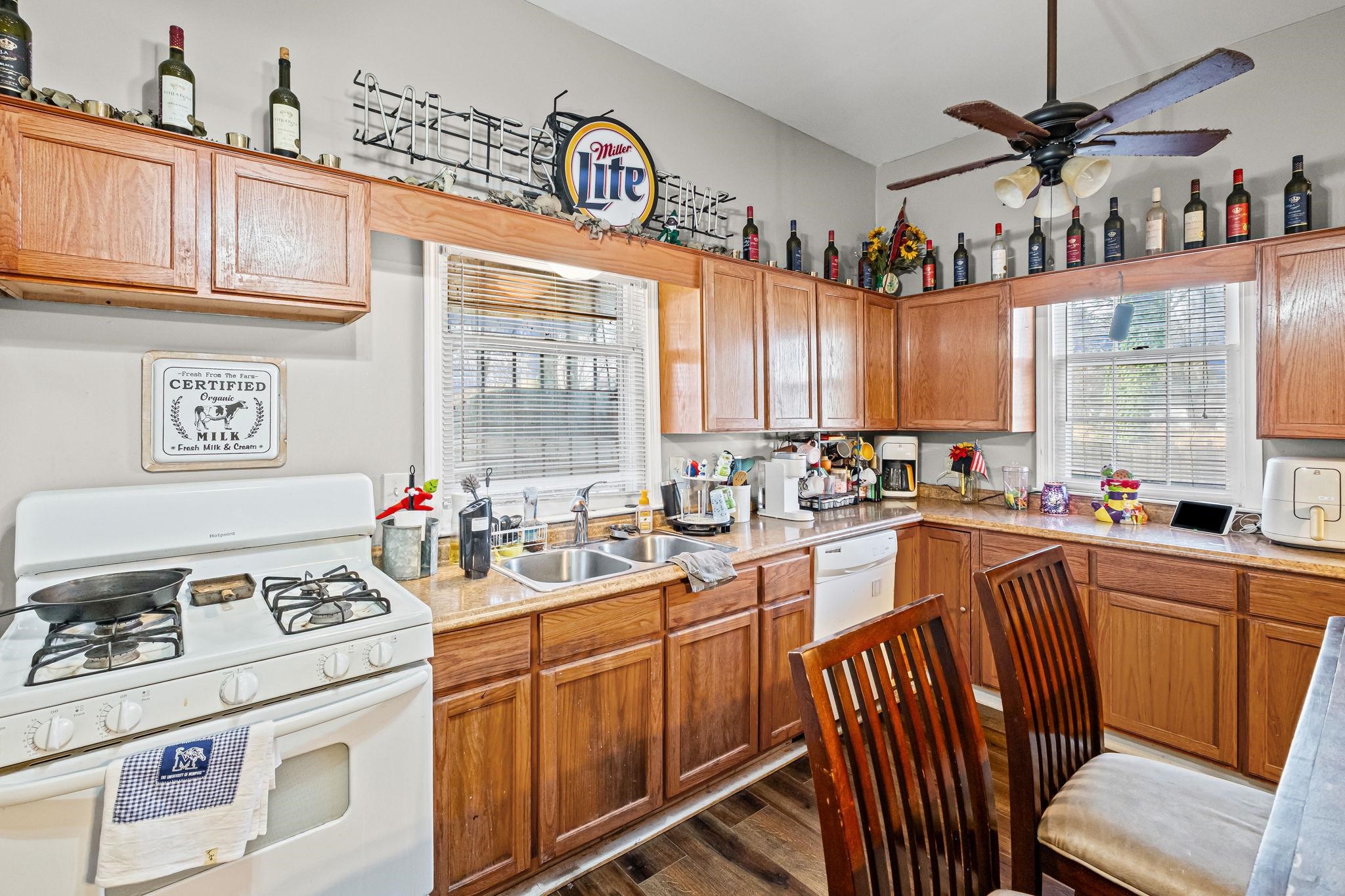 301 North Maple Street Covington, TN 38019 - Photo 16 of 26 a kitchen with a stove a sink dishwasher and white cabinets with wooden floor