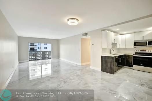 1901 South Ocean Drive, Unit 202 Hollywood, FL 33019 - Photo 8 of 11 a large kitchen with kitchen island a sink a stove a microwave a counter top and cabinets