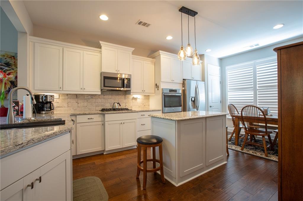 4014 Lavender Point Southwest Gainesville, GA 30504 - Photo 2 of 14 a kitchen with kitchen island granite countertop a stove a sink a oven a dining table and chairs with wooden floor