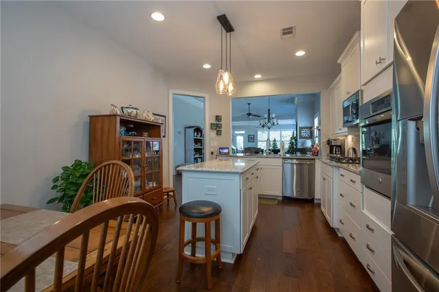 a kitchen with granite countertop white cabinets stainless steel appliances and dining table