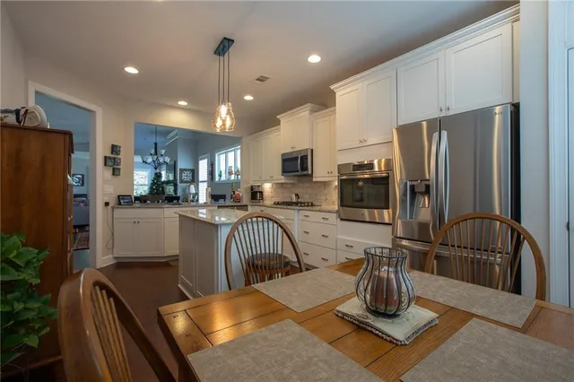 a kitchen with stainless steel appliances granite countertop a refrigerator a stove a sink dishwasher a dining table and chairs with wooden floor