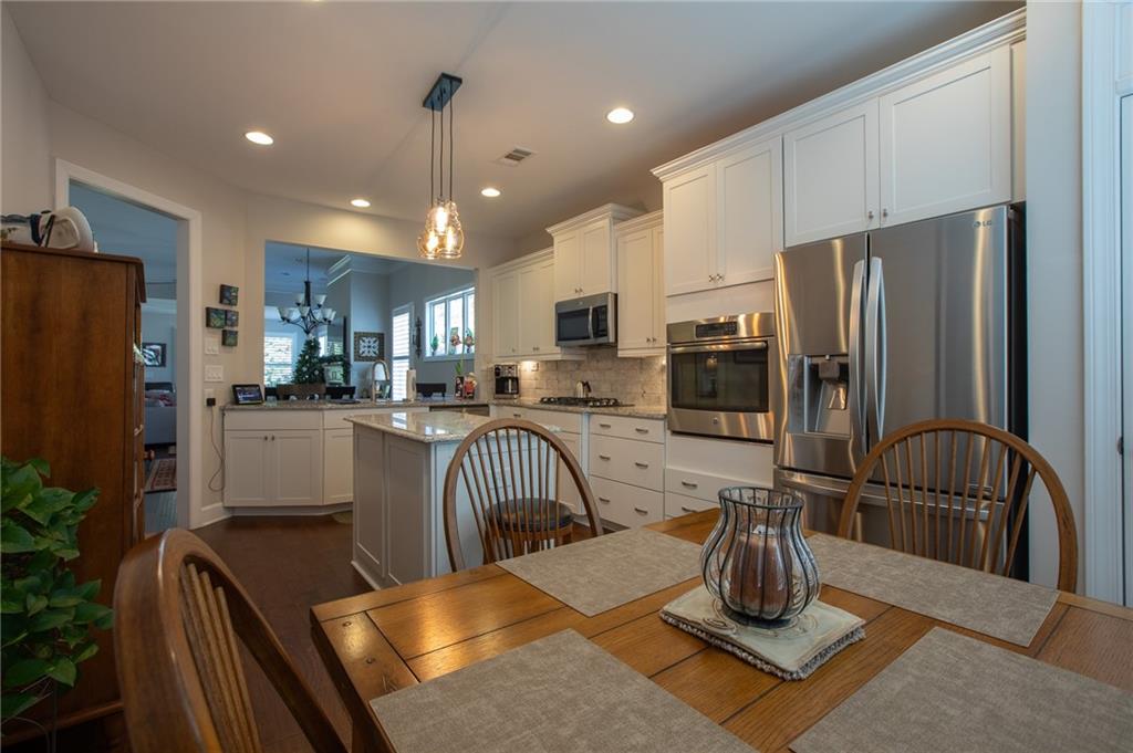 4014 Lavender Point Southwest Gainesville, GA 30504 - Photo 4 of 14 a kitchen with stainless steel appliances granite countertop a refrigerator a stove a sink dishwasher a dining table and chairs with wooden floor