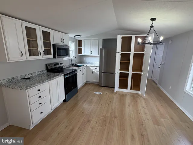 a kitchen with granite countertop a stove top oven a sink dishwasher a dining table and chairs with wooden floor