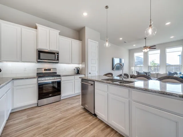 a kitchen with kitchen island granite countertop a sink cabinets and stainless steel appliances