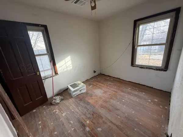 a view of empty room with wooden floor and fan