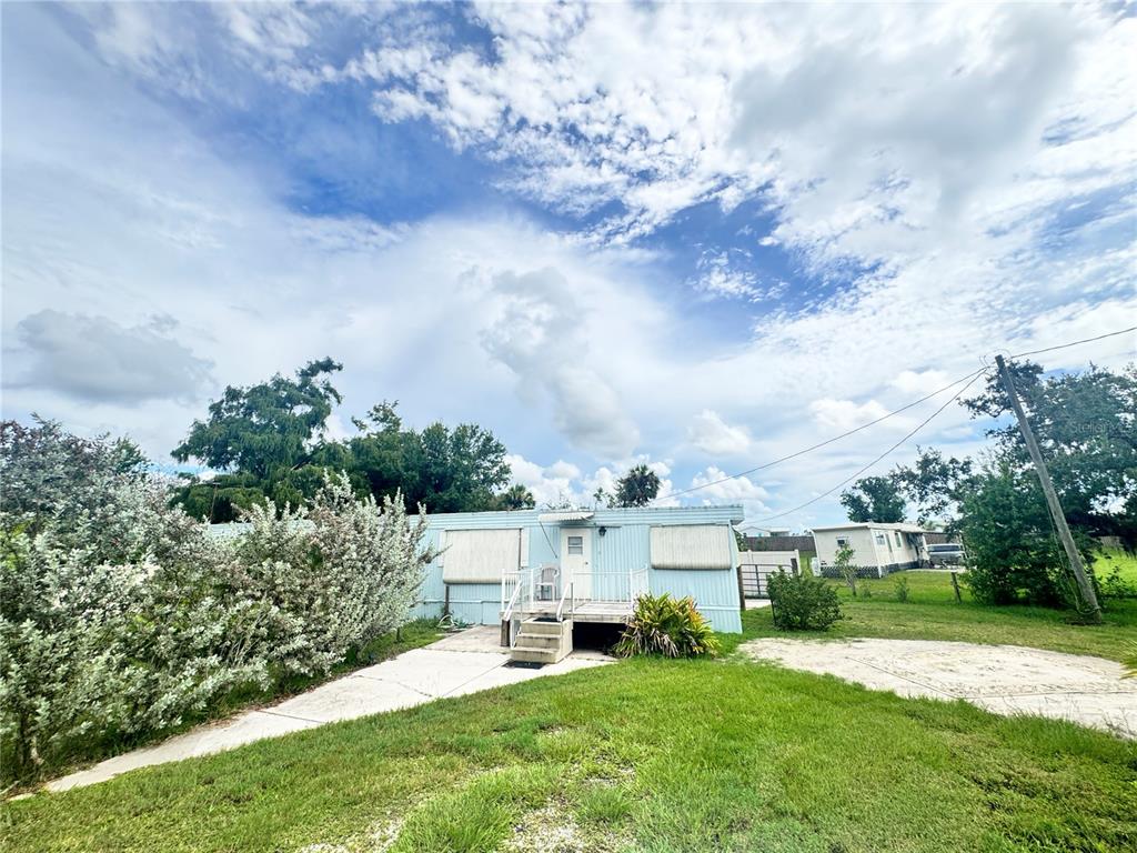 11970 Southwest Loop Terrace Arcadia, FL 34269 - Photo 35 of 37 a view of a white house in front of a big yard with plants and large trees