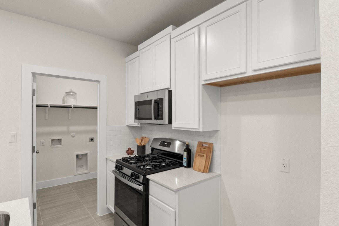 701 White Steppe Way Georgetown, TX 78626 - Photo 15 of 35 Kitchen featuring stainless steel appliances, white cabinets, tasteful backsplash, light stone countertops, and light tile patterned floors