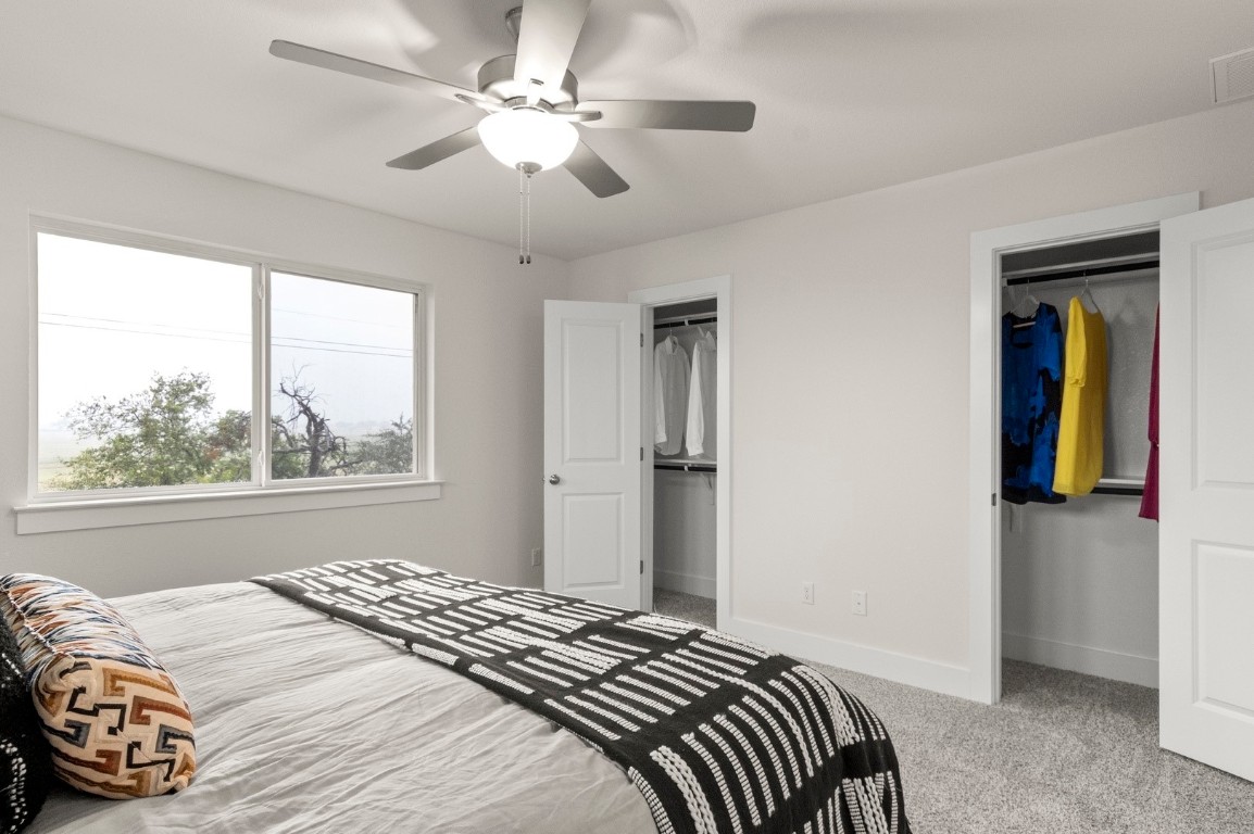 701 White Steppe Way Georgetown, TX 78626 - Photo 22 of 35 Bedroom with light colored carpet, a ceiling fan, and multiple closets