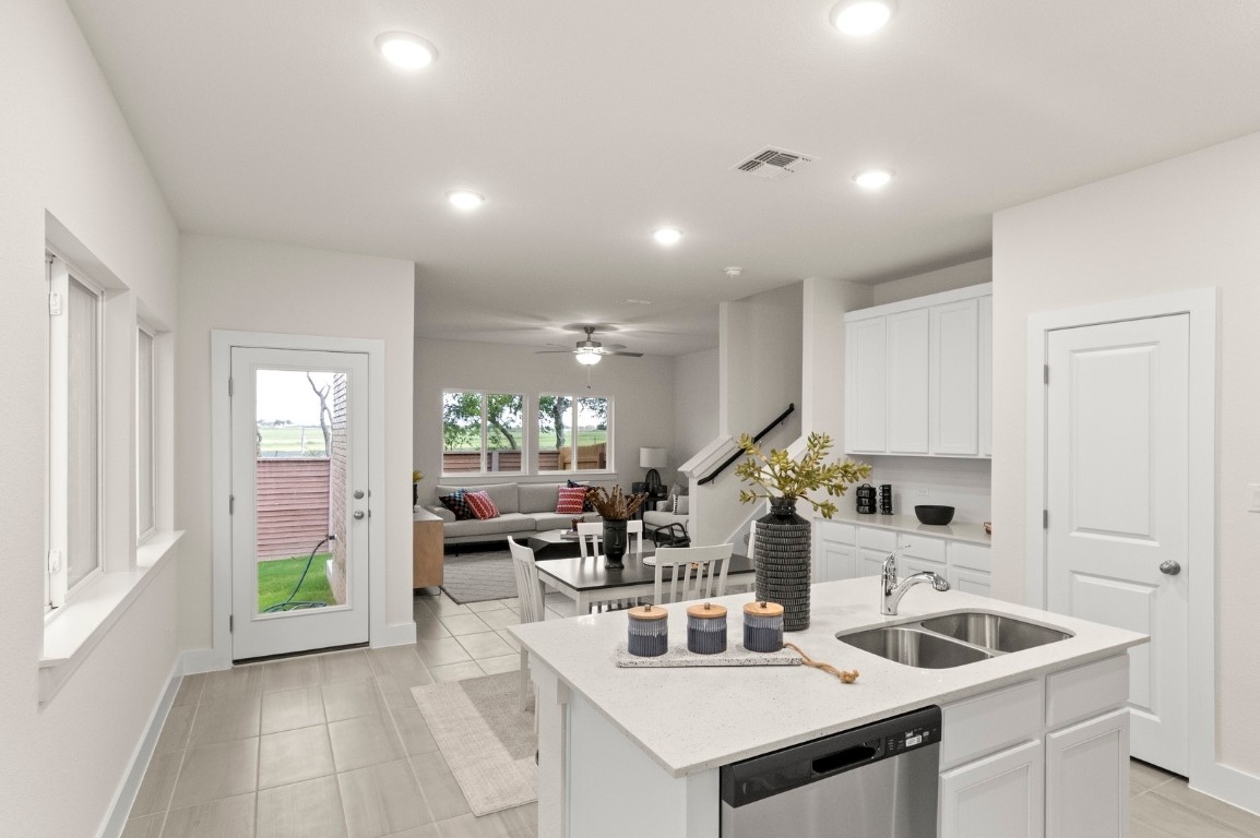 701 White Steppe Way Georgetown, TX 78626 - Photo 9 of 35 Kitchen with white cabinets, stainless steel dishwasher, an island with sink, light stone countertops, and light tile patterned flooring