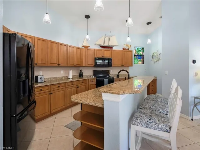 a kitchen with stainless steel appliances granite countertop a stove a sink a microwave a center island and a refrigerator