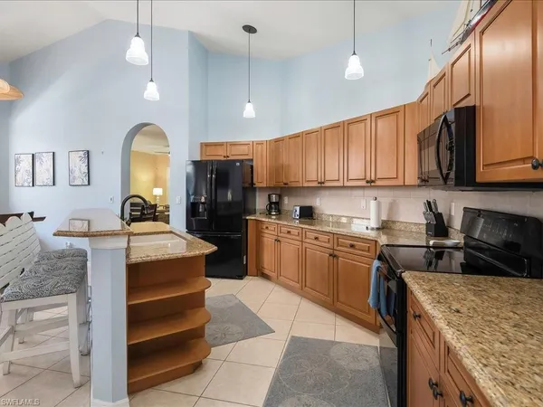 a kitchen with kitchen island granite countertop a stove top oven a sink a counter top space and cabinets