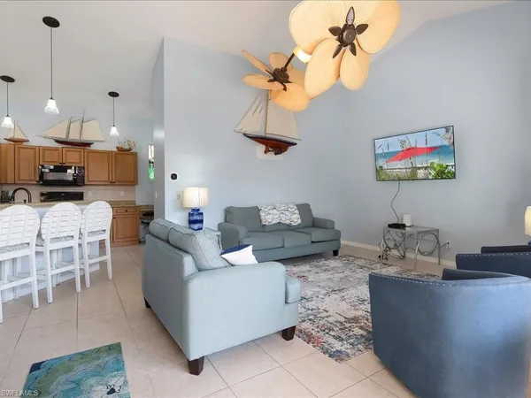a living room with couches a dining table and a chandelier with kitchen view