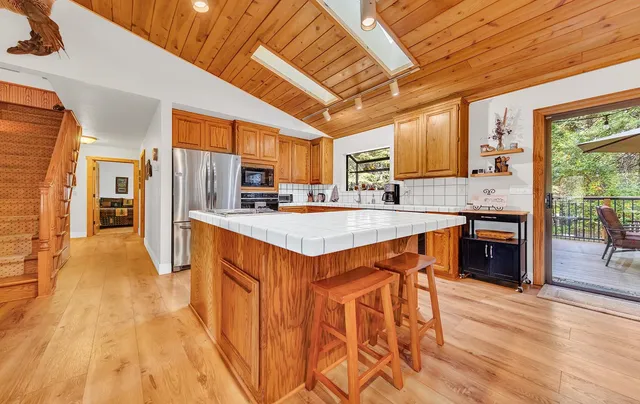 a kitchen with stainless steel appliances granite countertop a refrigerator a sink dishwasher a stove and white countertops with wooden floor