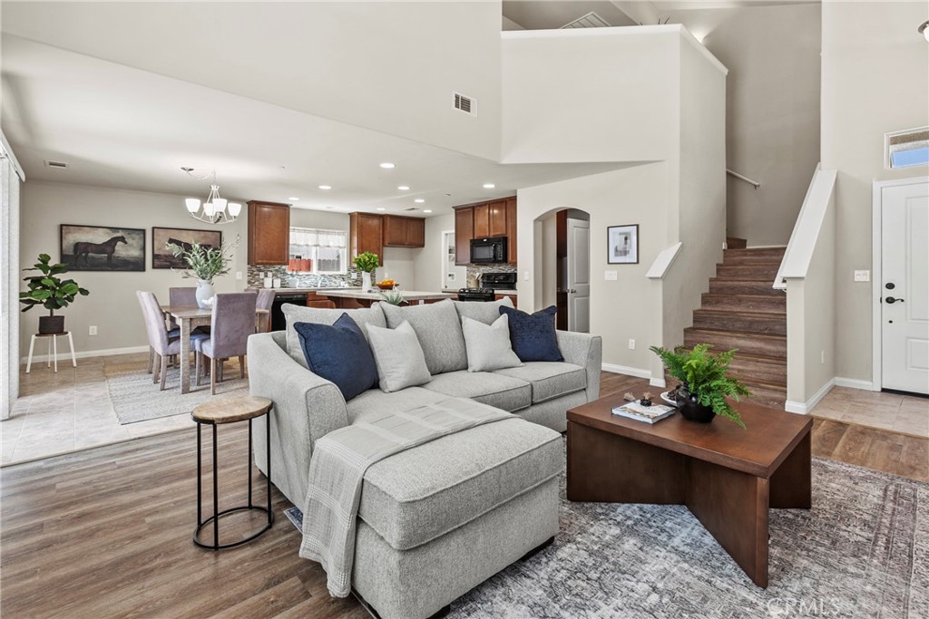 a living room with furniture potted plant and kitchen view
