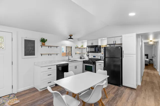 a kitchen with a refrigerator a stove a sink and a dining table with wooden floor