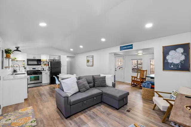 a living room with furniture kitchen view and a wooden floor