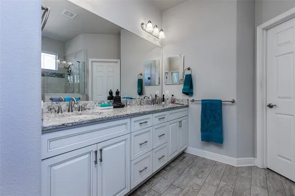 a bathroom with a granite countertop double vanity sink and a mirror