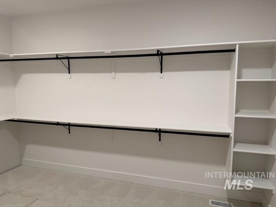 755 West Wrangler Street Meridian, ID 83646 - Photo 13 of 35 Spacious closet featuring white built-in shelving, black hanging rods, and light gray carpet flooring