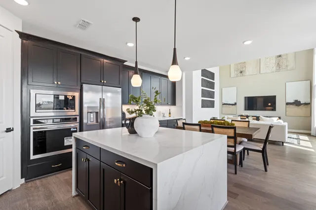 a kitchen with a stove a refrigerator a sink dishwasher with a dining table and chairs with wooden floor