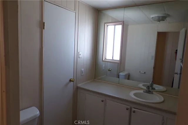 a bathroom with a granite countertop sink toilet and mirror
