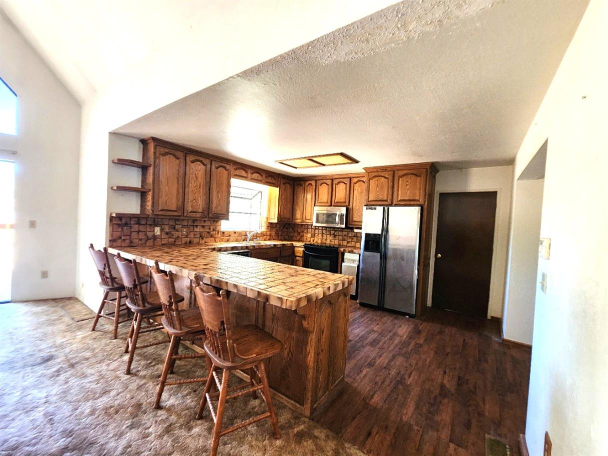 1925 Skull Flat Road West Point, CA 95255 - Photo 14 of 86 a kitchen with stainless steel appliances granite countertop a refrigerator a stove a sink and a dining table with wooden floor