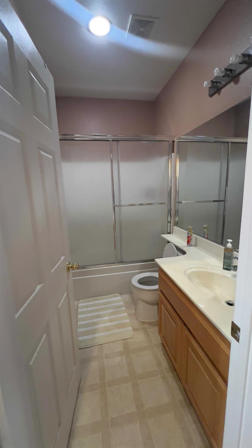5221 East Byrd Avenue Fresno, CA 93725 - Photo 13 of 15 a bathroom with a granite countertop sink a toilet and shower