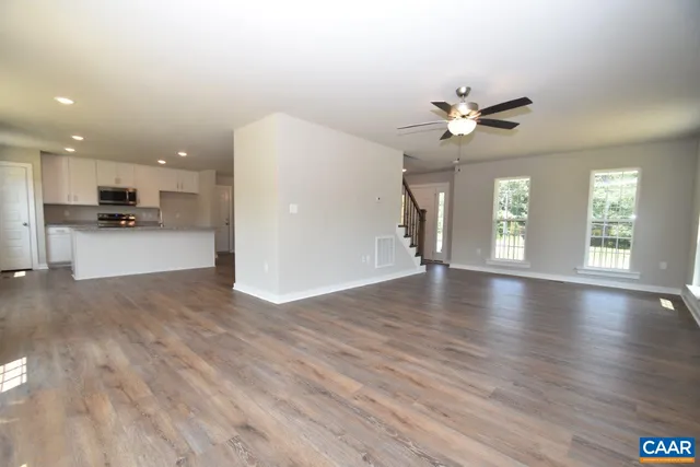 a view of an empty room with a kitchen and wooden floor