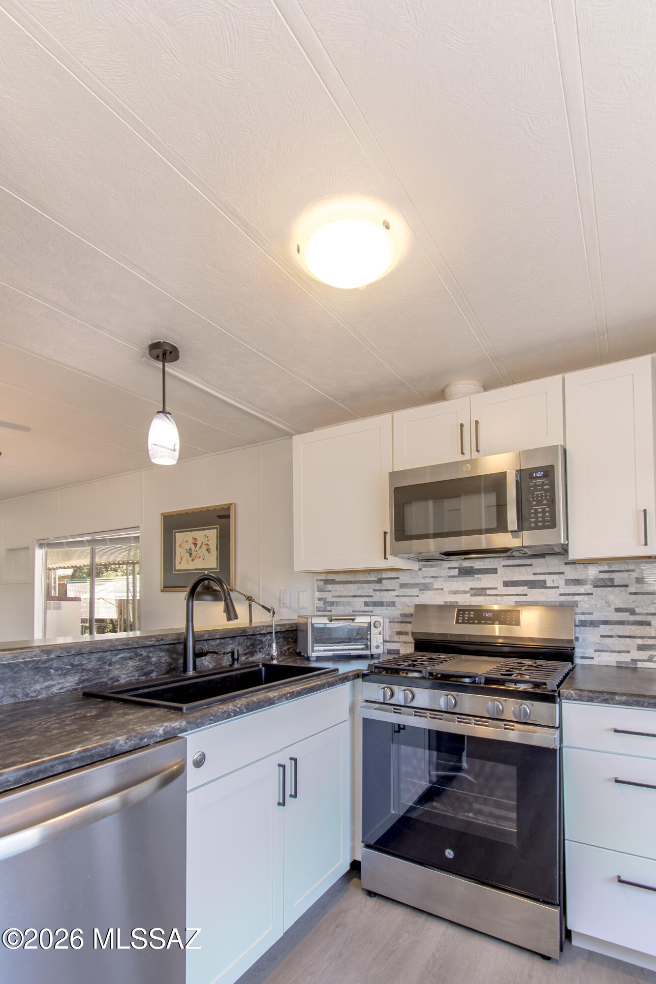 4550 North Flowing Wells Road, Unit 155 Tucson, AZ 85705 - Photo 13 of 40 a kitchen with kitchen island granite countertop a stove a sink and a microwave