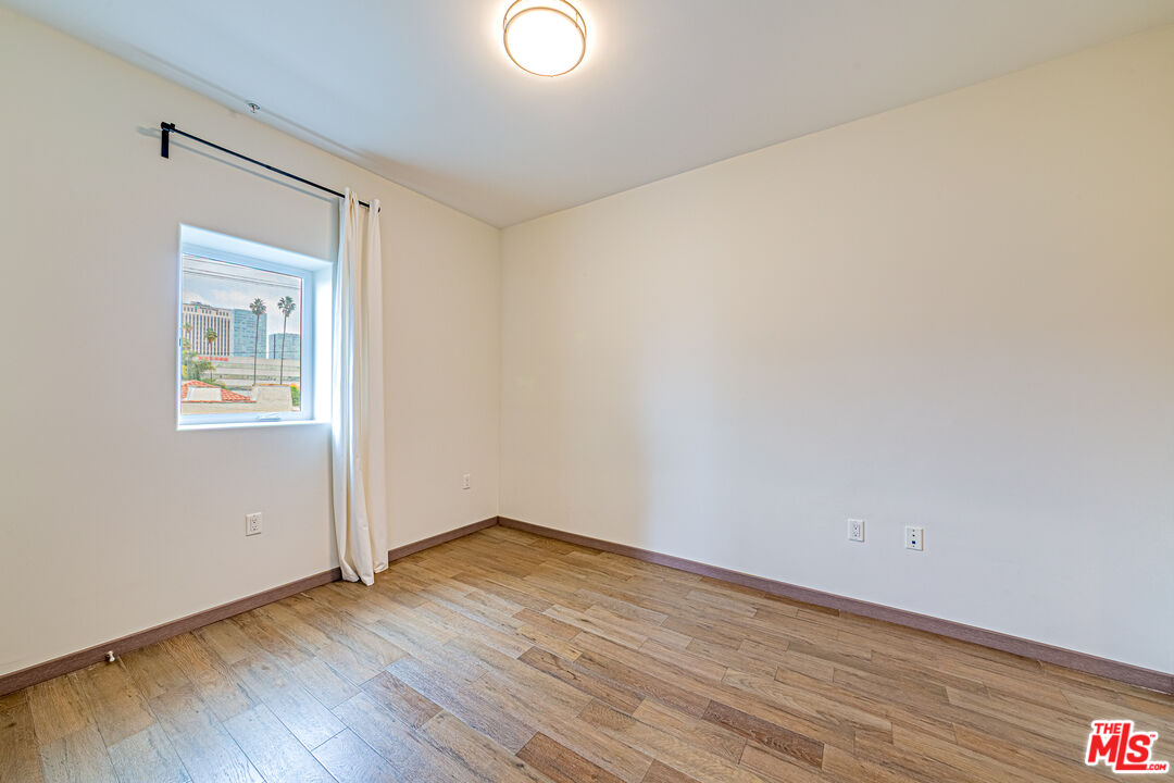 903 South New Hampshire Avenue, Unit 303 Los Angeles, CA 90006 - Photo 17 of 33 an empty room with wooden floor and a window