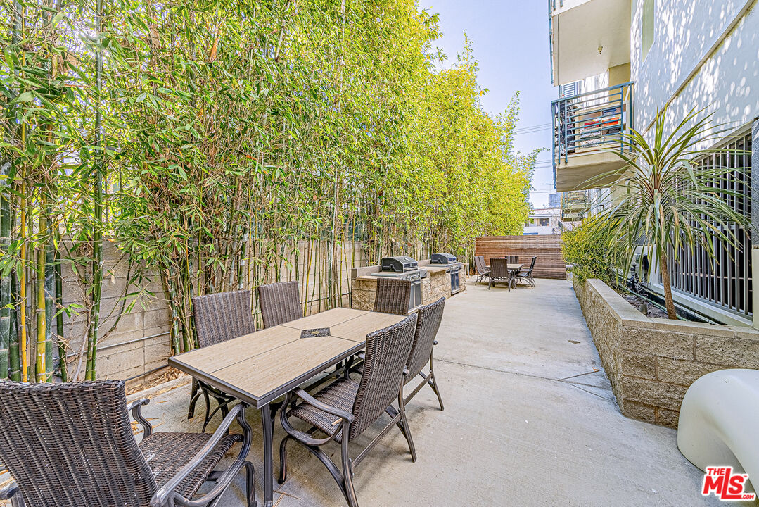 903 South New Hampshire Avenue, Unit 303 Los Angeles, CA 90006 - Photo 29 of 33 a view of a patio with table and chairs and potted plants with wooden fence