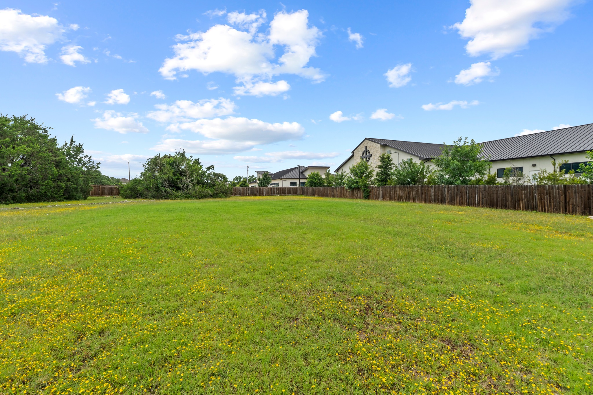 205 Sedro Trail Georgetown, TX 78633 - Photo 7 of 32 A spacious green parcel awaits your vision, bordered by a classic wooden fence and a blue sky.