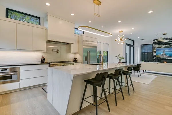a kitchen with stainless steel appliances kitchen island granite countertop a table chairs sink and cabinets