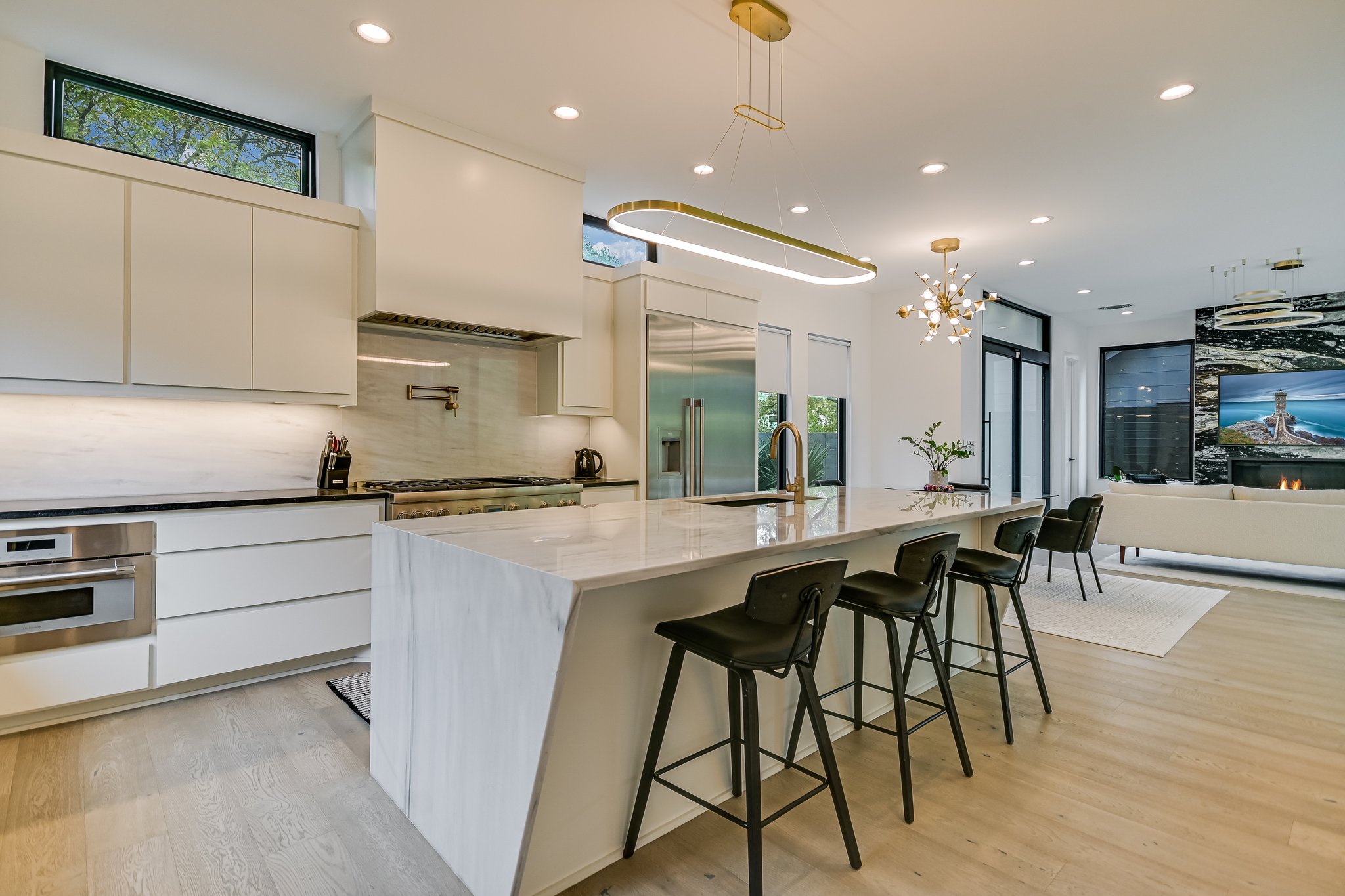 2015 De Verne Street Austin, TX 78704 - Photo 4 of 21 Kitchen featuring modern cabinets, decorative light fixtures, a kitchen bar, dark stone countertops, and light wood finished floors