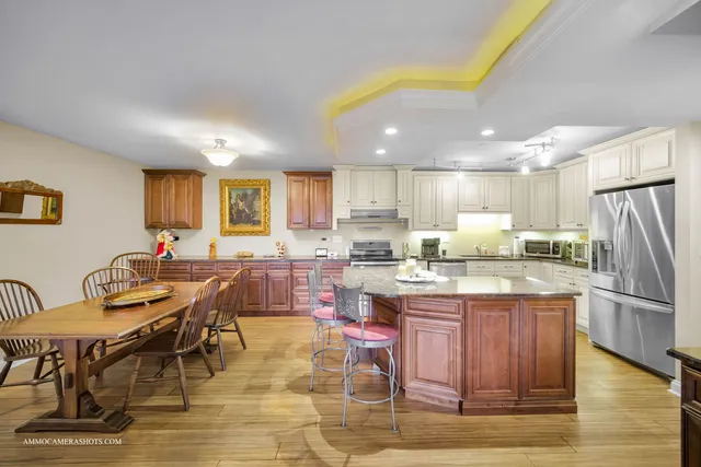a kitchen with stainless steel appliances kitchen island granite countertop a table chairs sink and cabinets