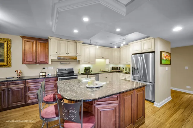 a kitchen with granite countertop kitchen island stainless steel appliances a sink stove and refrigerator