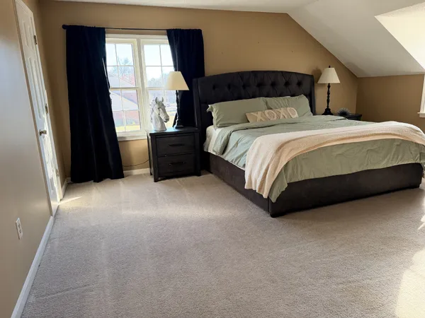 a bedroom with a bed lamp and a large window