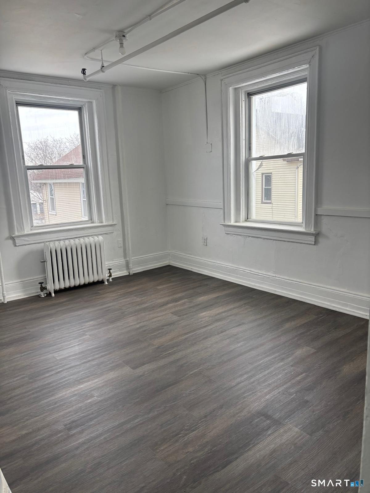 86 Pequonnock Street, Unit 32 Bridgeport, CT 06604 - Photo 2 of 4 an empty room with wooden floor and windows