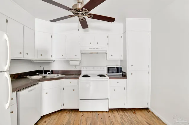 a kitchen with granite countertop white cabinets and white appliances