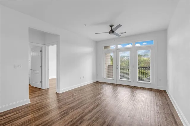 a view of an empty room with wooden floor and a window