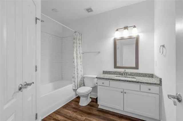 a bathroom with a granite countertop sink a toilet mirror and bathtub