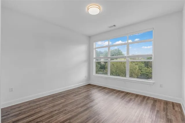 an empty room with wooden floor and windows