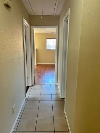 a view of a hallway with wooden floor and a bathroom