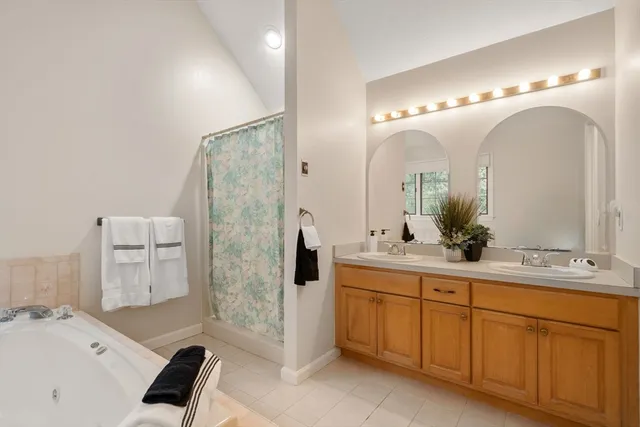 a spacious bathroom with a double vanity sink a toilet a mirror and shower